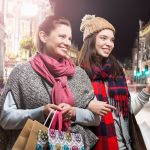 Mother and daughter shopping in busy street.